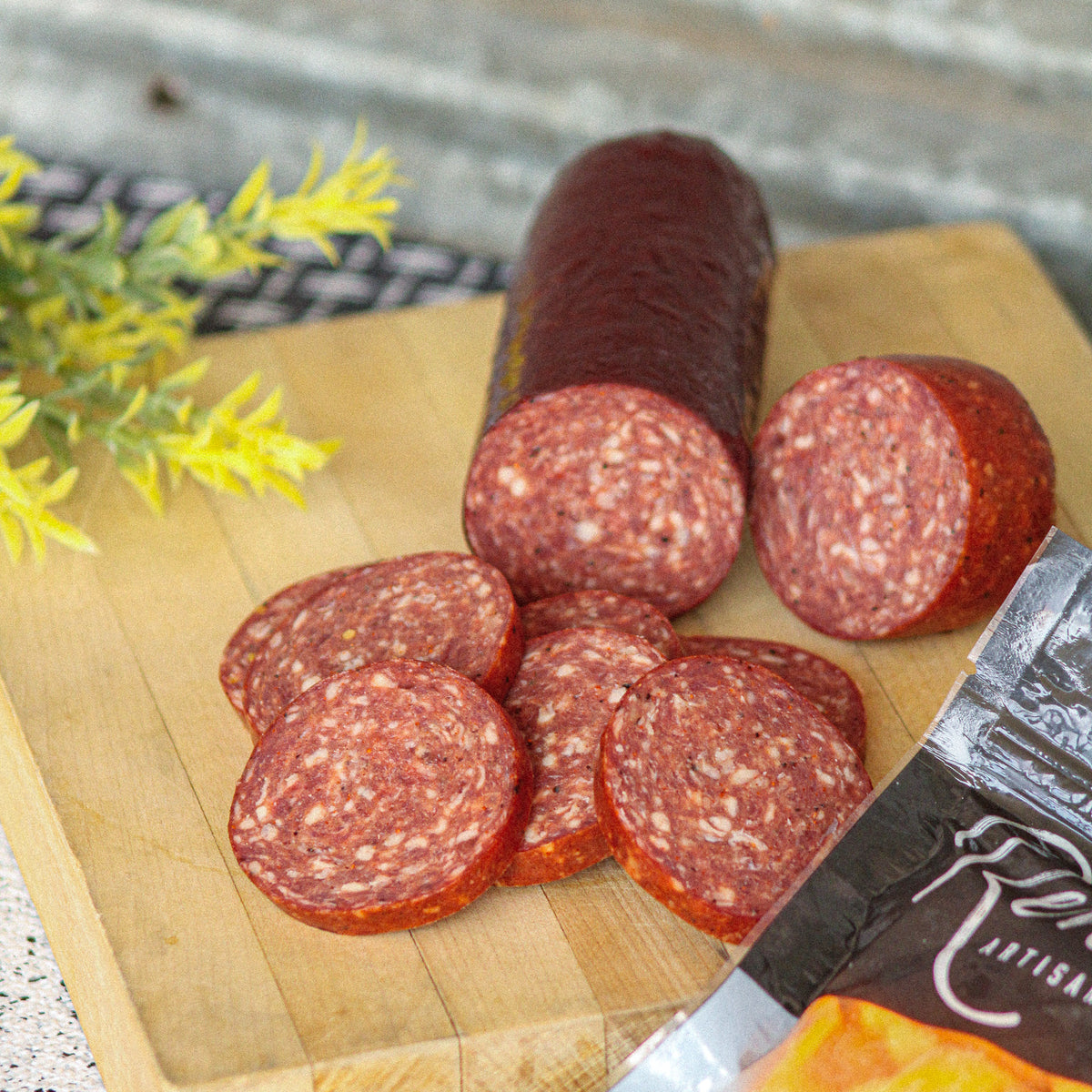No sugar added grass-fed beef summer sausage, sliced on a wooden board